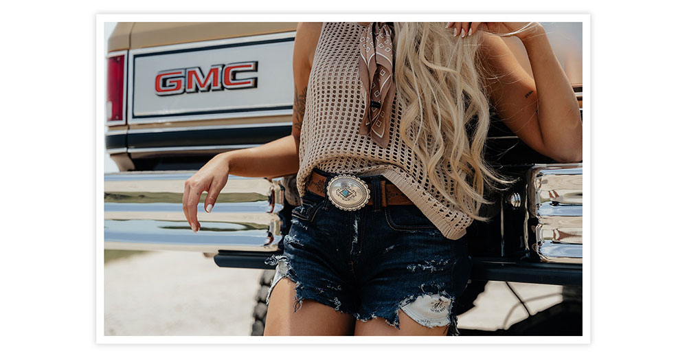 A woman with blonde hair posing wearing her ladies native heart belt in brown.